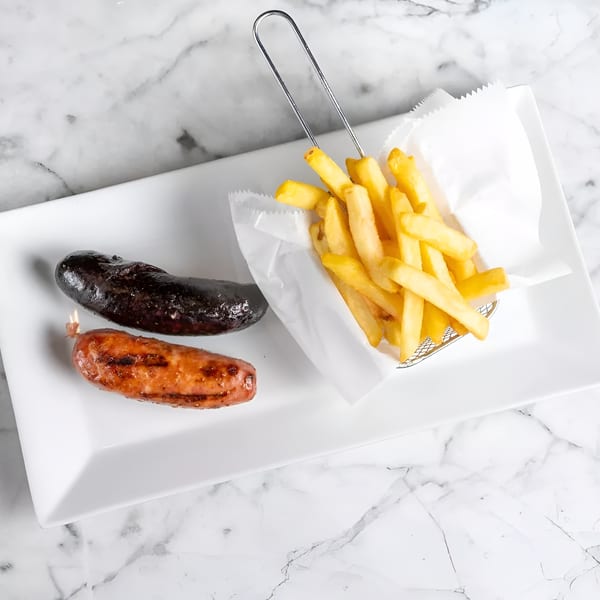 Two grilled sausages, one dark and one lighter, with a side of golden french fries.