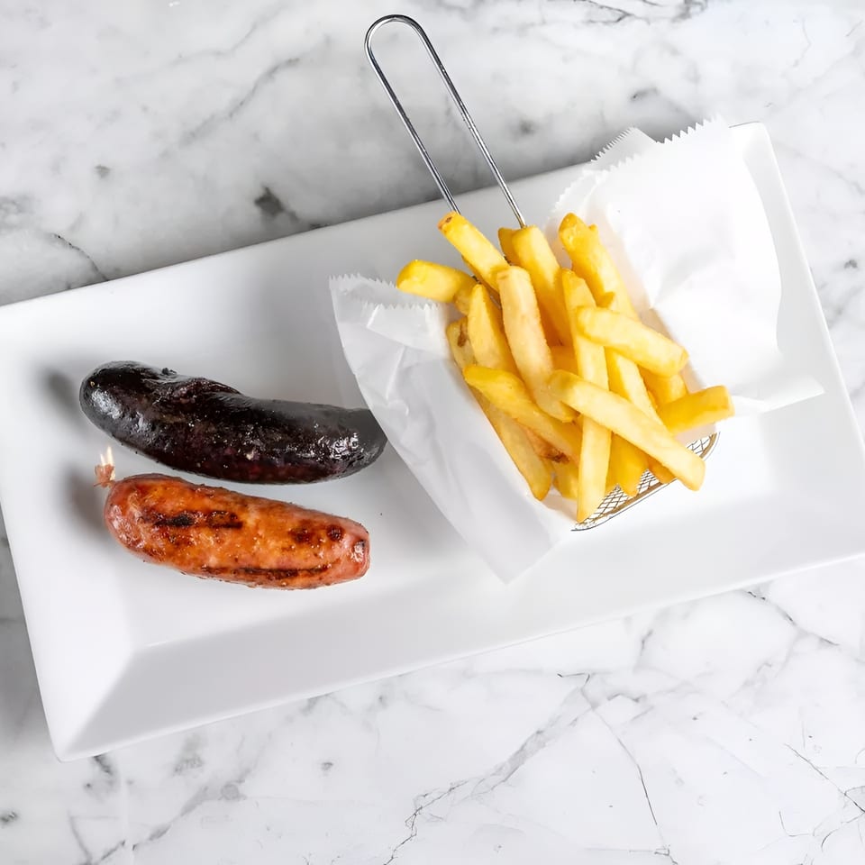 Two grilled sausages, one dark and one lighter, with a side of golden french fries.