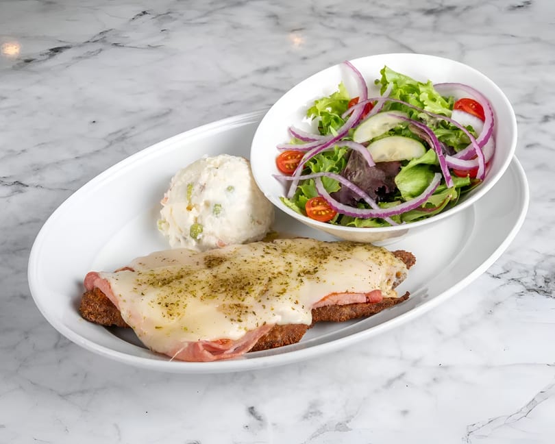 Milanesa Napolitana with melted cheese and ham, served with potato salad and a side salad.