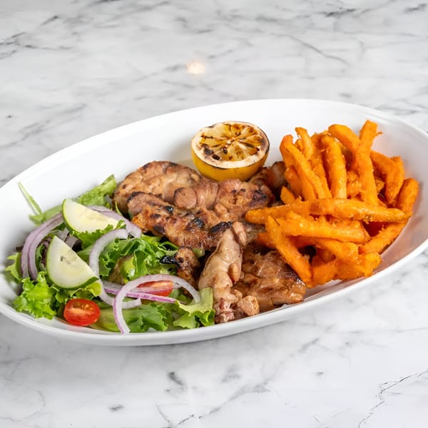 Grilled chicken, sweet potato fries, and a fresh salad with cucumber, onion, and tomato.