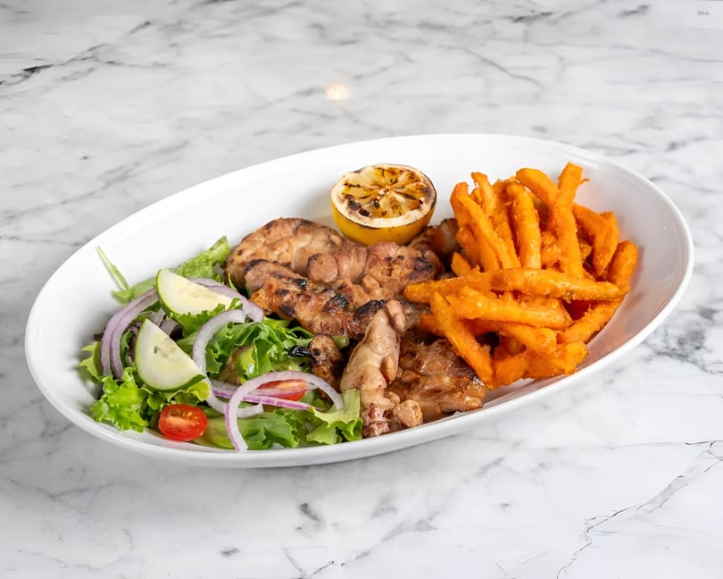 Grilled chicken, sweet potato fries, and a fresh salad with cucumber, onion, and tomato.