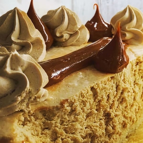 Close-up of a cheesecake with dulce de leche and coffee-flavored whipped cream swirls.